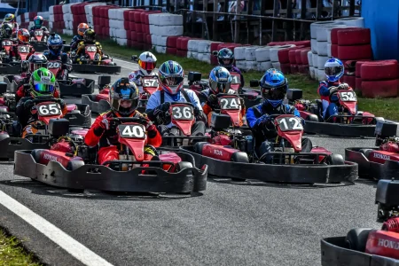 Pilotos alinhados em corrida de campeonato de kart rental, com diferentes categorias e disputa intensa em pista outdoor organizada pela AMIKA Kart.