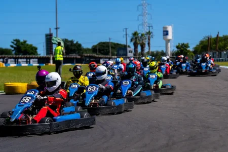 Pilotos alinhados durante corrida de kart rental em pista outdoor, com disputa intensa e formação do grid durante a prova.
